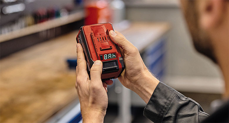 A man holding a Power-X-Change battery in the workshop.