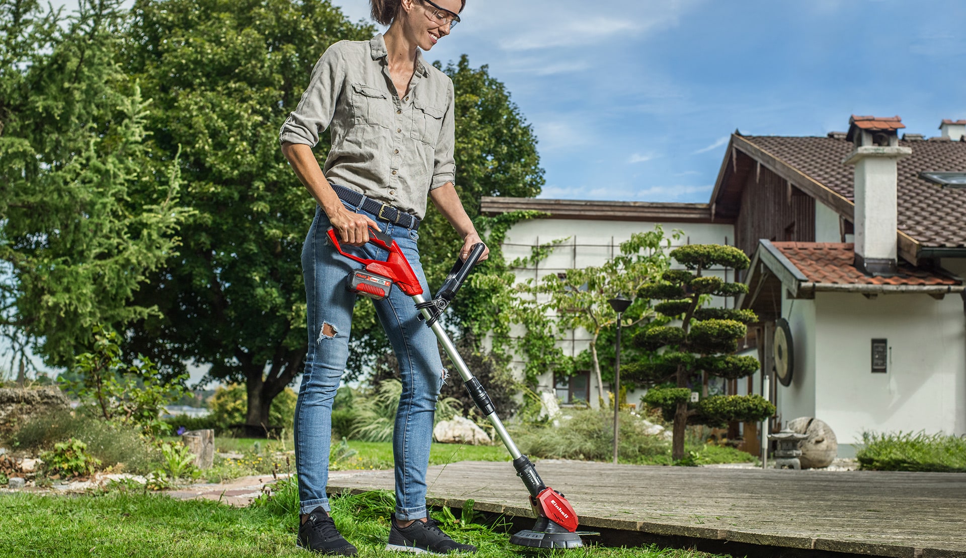 A woman trims the grass on a jetty