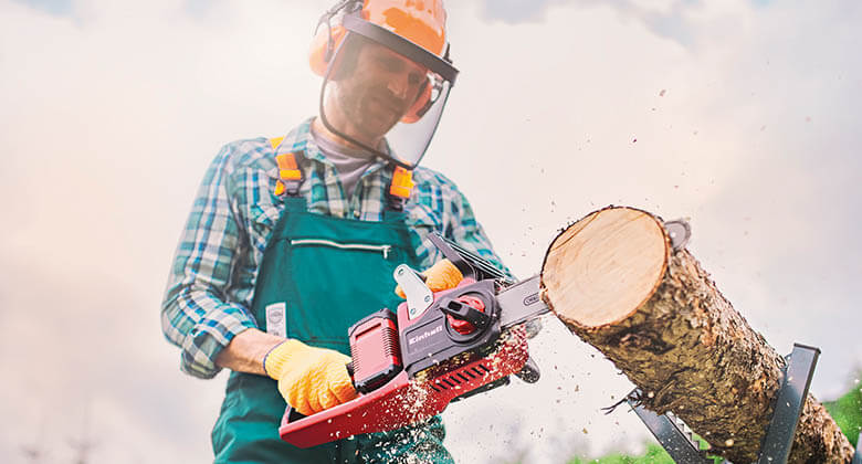 a man cuts a tree trunk with a chainsaw